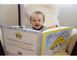 Baby smiling reading Oliver Poons and the Bright Yellow Hat